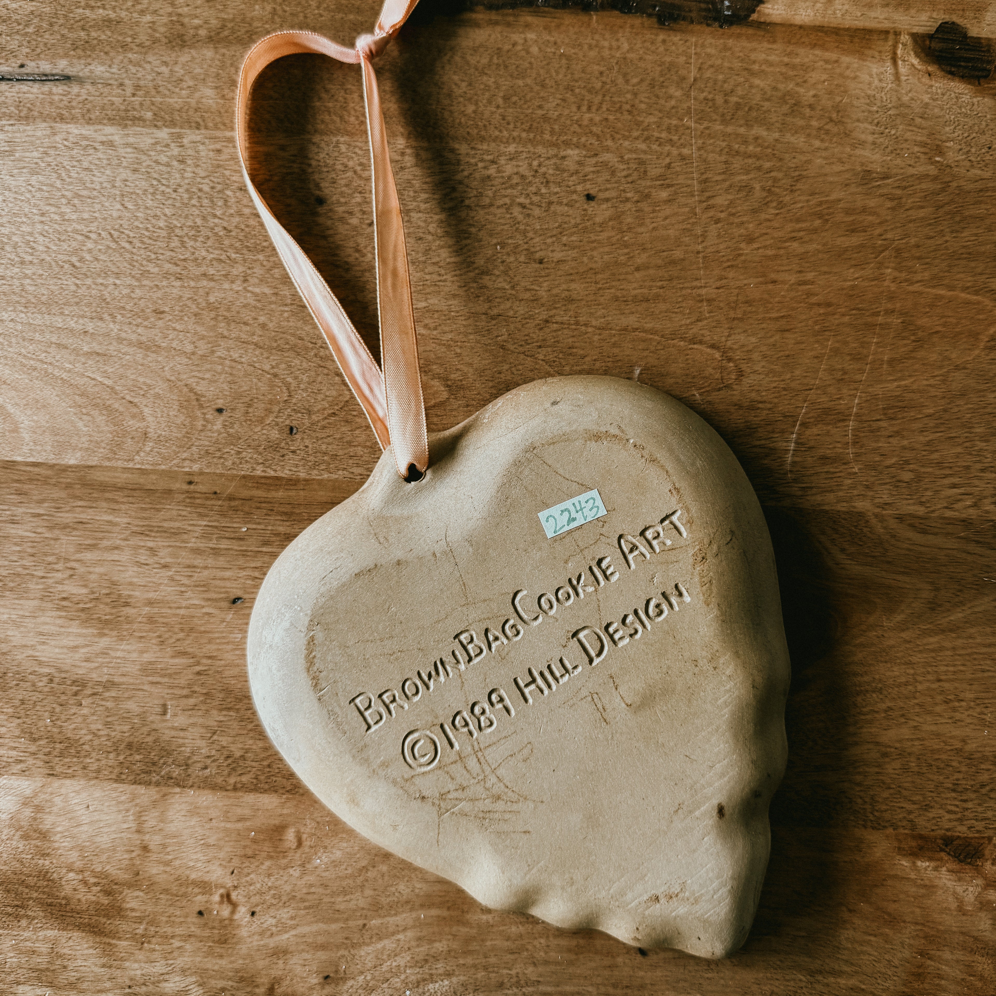 Back side of A tan-colored, heart-shaped stoneware cookie mold with Brown Bag Cookie Art marked in 1989 Hill Design