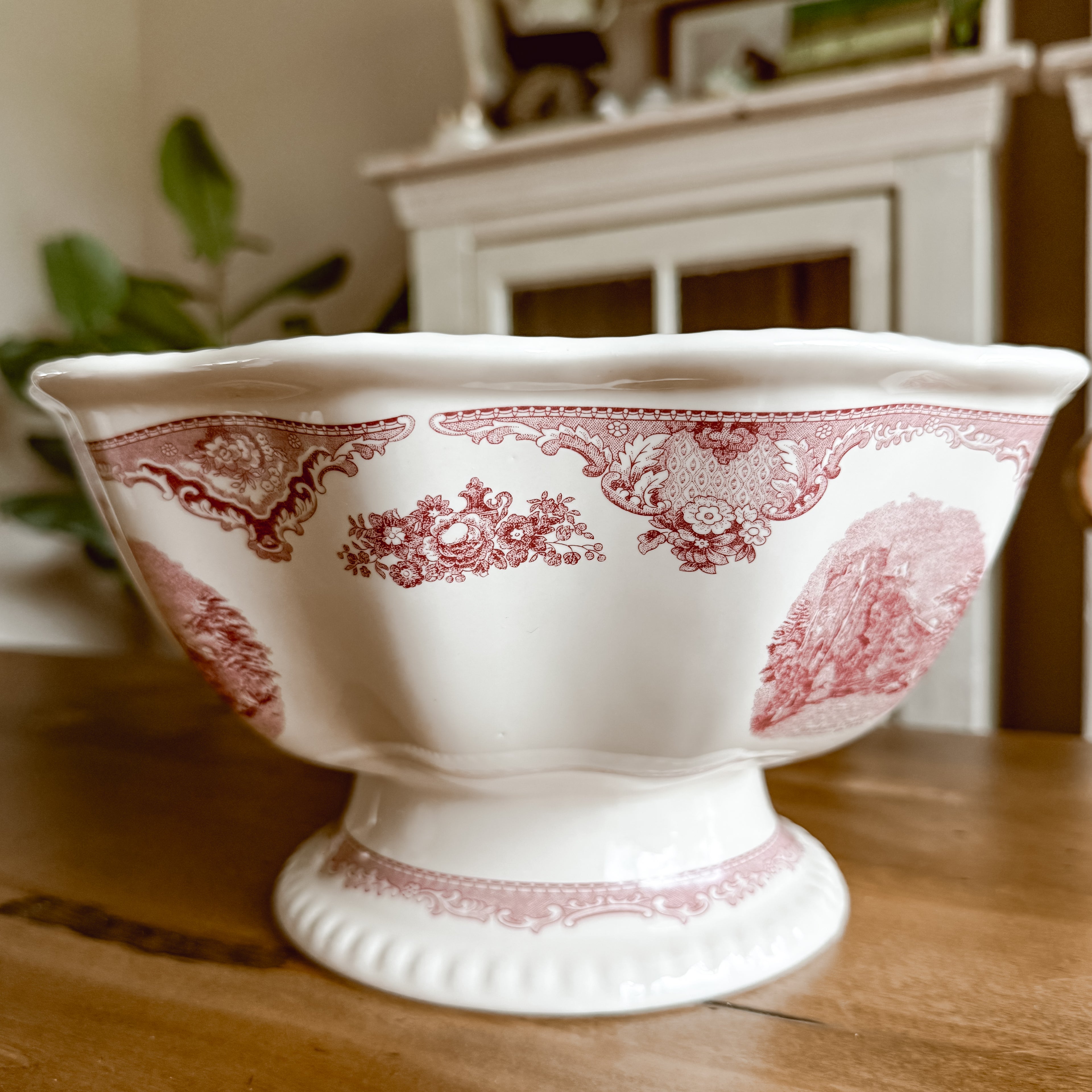 Side view of Johnson Brothers Old Britain Castles pink pedestal fruit bowl highlighting the footed base and wavy rim detail