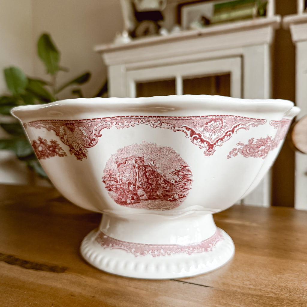 Side view of Johnson Brothers Old Britain Castles pink pedestal fruit bowl highlighting the footed base and wavy rim detail