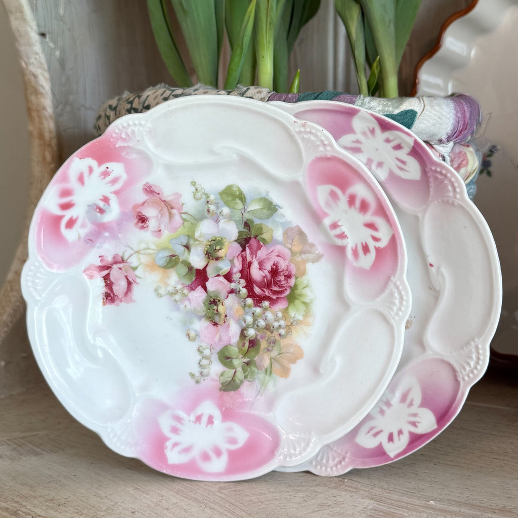 Antique German porcelain dessert plate featuring a central bouquet of pink roses and white lilies with a scalloped edge and pink airbrushed borders.