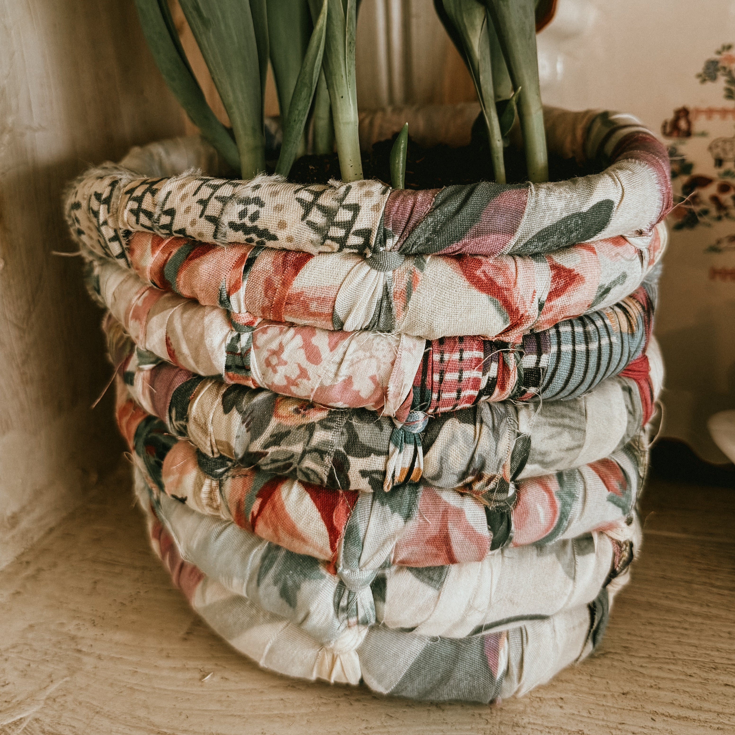 handmade vintage coiled rag basket featuring multi-colored floral and plaid fabric strips 