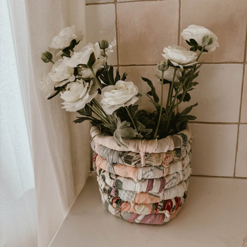 handmade vintage coiled rag basket featuring multi-colored floral and plaid fabric strips 
