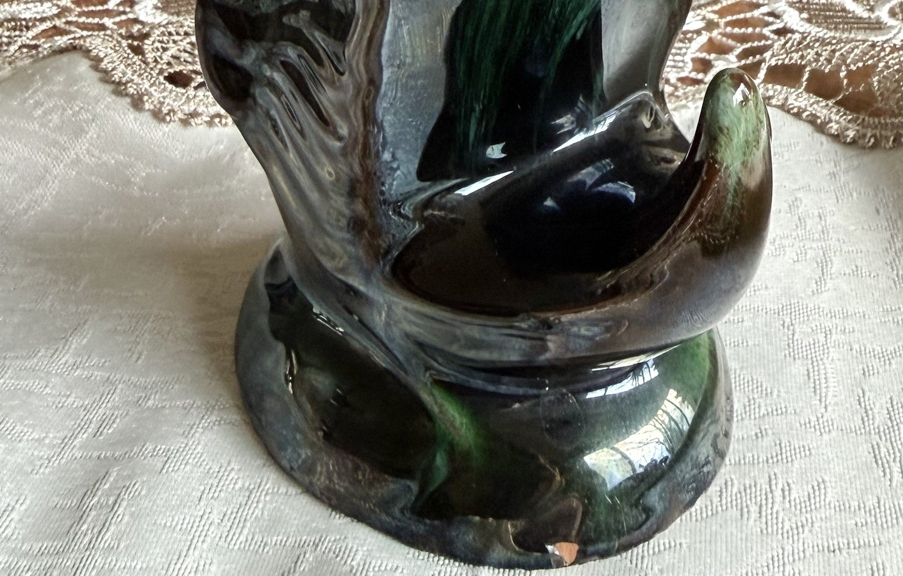 Close-up of the base and tail section, showing the intricate glaze details and a small chip near the bottom.